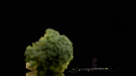 Ein-Frischer-Grüner-Brokkoli-Fällt-In-Zeitlupe-Auf-Ein-Glas-Mit-Spritzern-Und-Wassertropfen